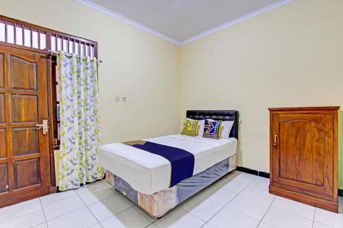 a small bedroom with a bed and a wooden door at SPOT ON 93007 Guest House Lestari in Prambanan