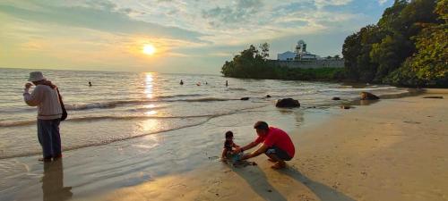 een man die met een kind speelt op het strand bij Homestay Anak Kito@Teluk Kemang Port Dickson in Port Dickson
