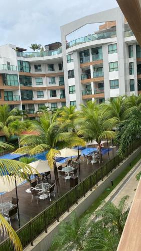 a courtyard with tables and palm trees in front of a building at Luxor Paulo Miranda Frente ao mar in João Pessoa