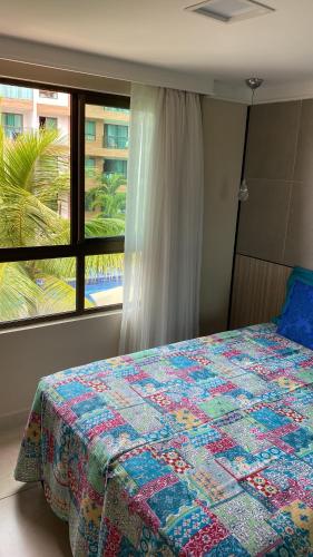 a bedroom with a quilt on a bed and a window at Luxor Paulo Miranda Frente ao mar in João Pessoa