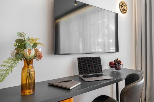 a desk with a laptop and a vase of flowers at Tatry Mozaika Willa PREMIUM & SPA - Sauna, Jacuzzi, Flipper by RentiloPL in Zakopane