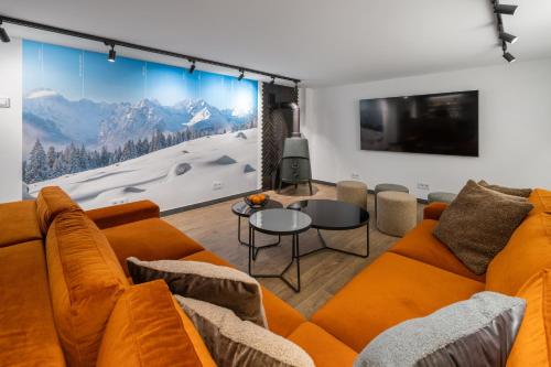 a living room with an orange couch and a tv at Tatry Mozaika Willa PREMIUM & SPA - Sauna, Jacuzzi, Flipper by RentiloPL in Zakopane