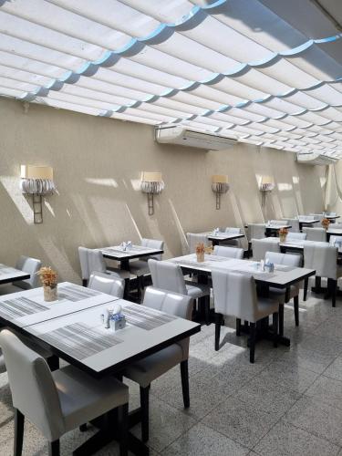 a dining room with tables and white chairs at Tropical Barra Hotel in Rio de Janeiro