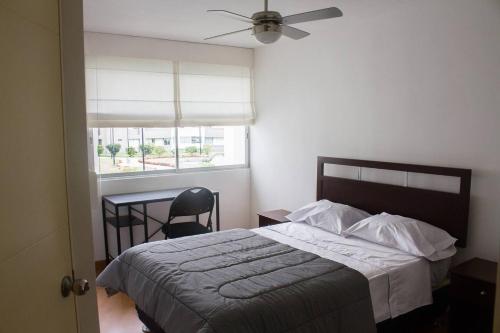 1 dormitorio con cama, escritorio y ventana en DEPARTAMENTO EN SURCO, en Lima