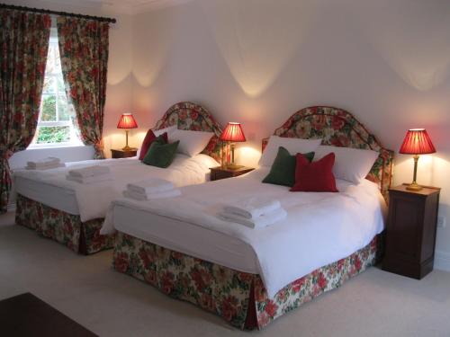 two beds in a bedroom with red and green pillows at Delphi Lodge in Leenaun