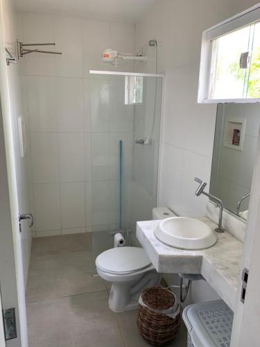 a white bathroom with a toilet and a sink at Flat amplo em condominio beira mar in São Miguel do Gostoso