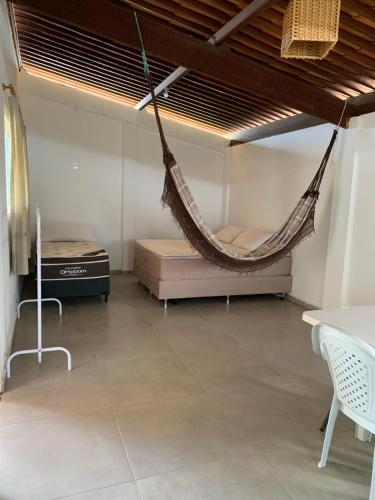 a hammock in a room with two beds and a table at Flat amplo em condominio beira mar in São Miguel do Gostoso