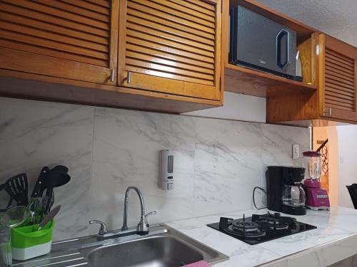 a kitchen with a sink and a stove and a microwave at Casa Las Palmas in Cancún