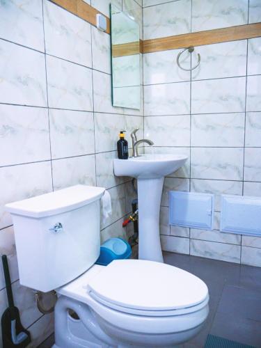 a bathroom with a white toilet and a sink at Cecay Apartments Logpom in Douala