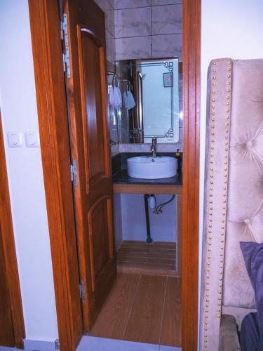 a small bathroom with a sink and a mirror at Cecay Apartments Logpom in Douala