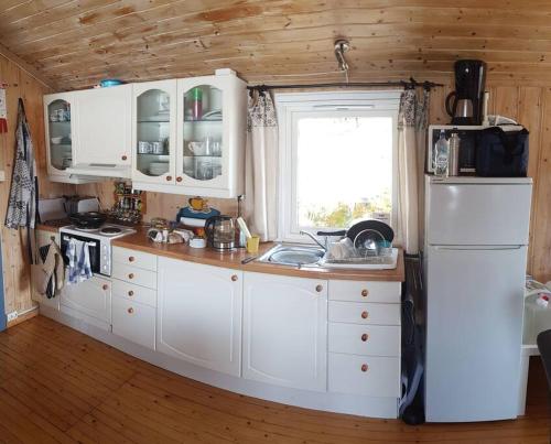 a kitchen with white cabinets and a white refrigerator at Idyllic lakeside cabin (hytte) in Horten