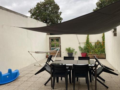 a patio with a table and chairs and a black canopy at Maison tout confort in Corbie