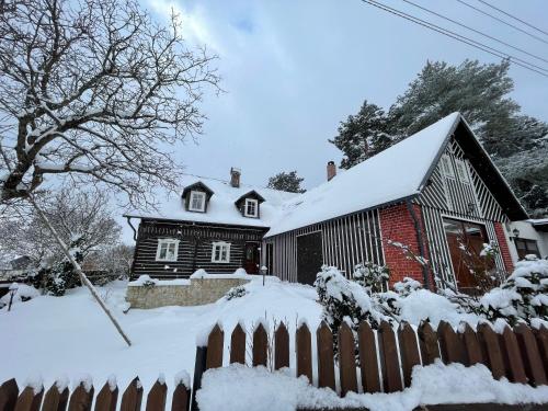 a house covered in snow with a fence at Exkluzivní chalupa Podještědka s grilem a saunou in Světlá pod Ještědem