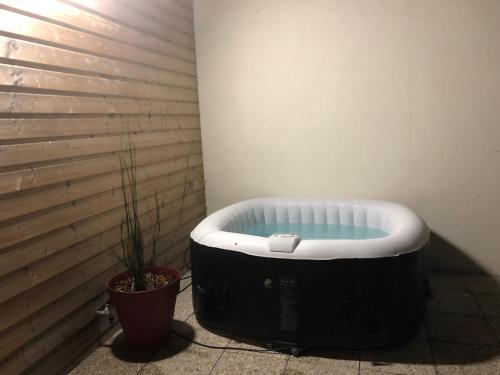 a bath tub sitting in a corner with a plant at Maison tout confort in Corbie