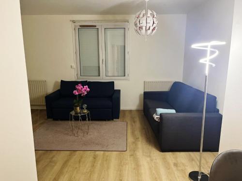 a living room with a blue couch and a table at Logement entier chambre+salon + jardin & terrasse in Les Ulis