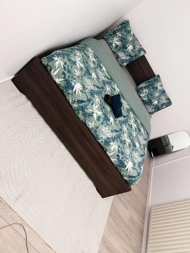 a bed with a green and white comforter at Logement entier chambre+salon + jardin & terrasse in Les Ulis
