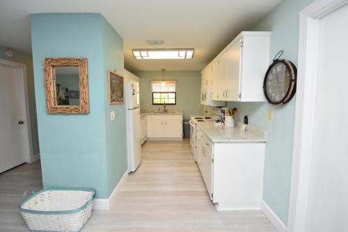 a kitchen with white cabinets and a blue wall at HIDDEN OASIS Spacious Pool Home with Florida Room and Hot Tub in Palm Coast