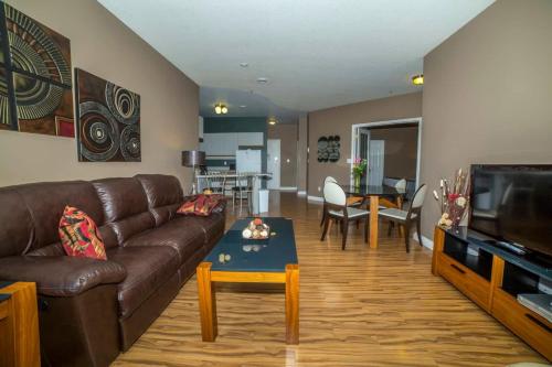 a living room with a brown couch and a table at Obasa Suites @ The Hamilton in Regina