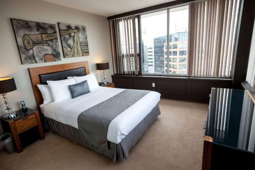 a bedroom with a large bed and a large window at Obasa Suites @ The Hamilton in Regina
