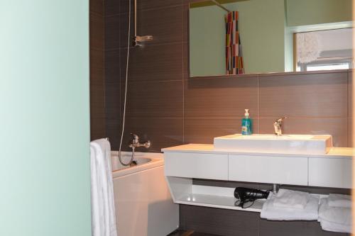 a bathroom with a sink and a mirror and a tub at Lisbon Brown Cozy Apartment in Lisbon