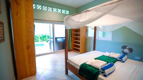 - une chambre avec un lit à baldaquin dans l'établissement The Pool House & The Colobus House, Bella Seaview, Diani Beach, Kenya, à Diani Beach