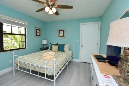 a bedroom with blue walls and a bed with a ceiling fan at HIDDEN OASIS Spacious Pool Home with Florida Room and Hot Tub in Palm Coast