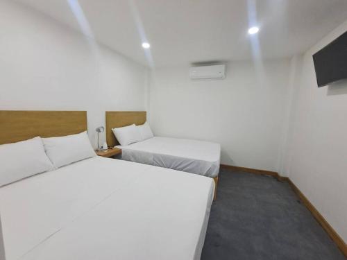 Fortín de las Floresにあるlugar para descansar210の白い部屋にベッド2台が備わるベッドルーム1室