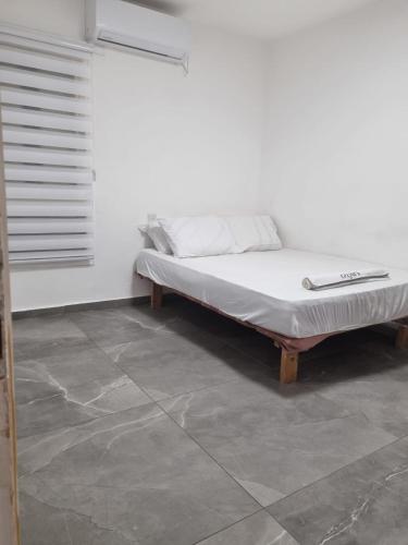 a bed sitting in a room with a white wall at דירה בסטייל in Eilat