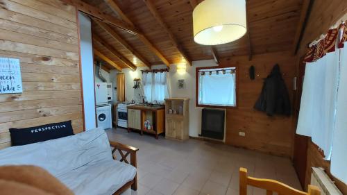 um quarto num chalé de madeira com uma cama e uma cozinha em Cabañas Kuky em San Carlos de Bariloche
