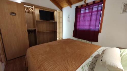 um quarto com uma cama e uma janela roxa em Cabañas Kuky em San Carlos de Bariloche