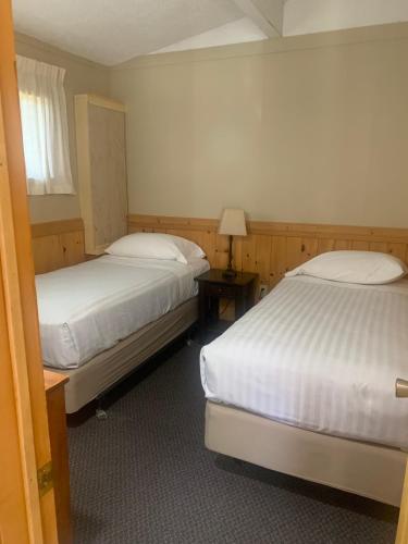 a room with two beds and a lamp on a table at Colonial Bay Motel and Cottages in Huntsville