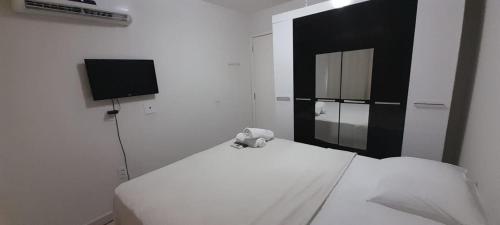 1 dormitorio con 1 cama blanca y TV en Brisas do Cabo Branco, en João Pessoa