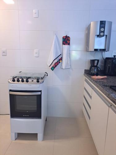 a white kitchen with a stove and a counter at Guarajuba Paraiso dos Coqueiros B02 in Camaçari