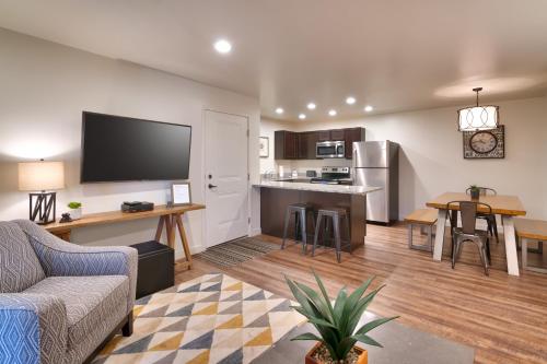 2G New Moab RedCliff Condo, Pool & Hot Tub في موآب: غرفة معيشة مع أريكة ومطبخ
