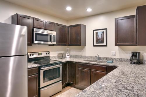 a kitchen with wooden cabinets and a stainless steel refrigerator at 2G New Moab RedCliff Condo, Pool & Hot Tub in Moab