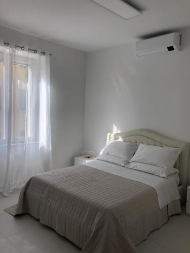 a white bedroom with a large bed and a window at Casa Vacanze Il Divano Rosso in Foligno
