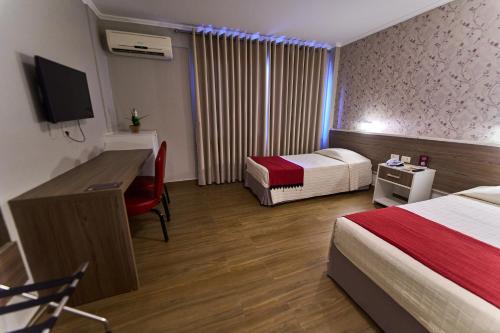 a hotel room with two beds and a desk and a television at Foz Plaza Hotel in Foz do Iguaçu