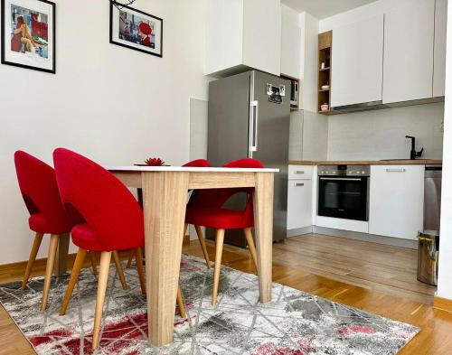 cocina con mesa de madera y sillas rojas en Apartman Pale Jahorina, en Pale