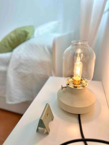 a candle in a glass jar on a table next to a bed at Apartamento St Agustí - Centro in Mataró