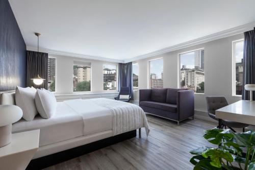 a hotel room with a bed and a chair and windows at SENS Høtel in Montréal