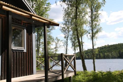 a cabin with a deck and a view of a lake at Holiday Home Tobo Gard in Storebro