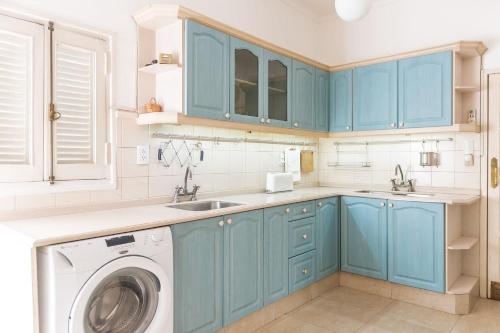cocina con armarios azules y lavadora en Casa Magnolia by Vilvey Turismo en Mendoza
