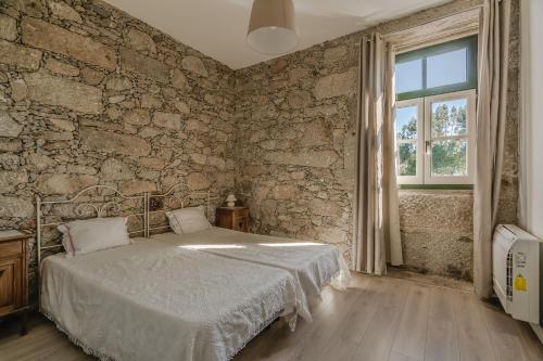 a bedroom with a bed and a stone wall at Quinta Calheiros - Rural Place in Coucieiro