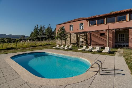 a swimming pool in front of a house at Quinta Calheiros - Rural Place in Coucieiro