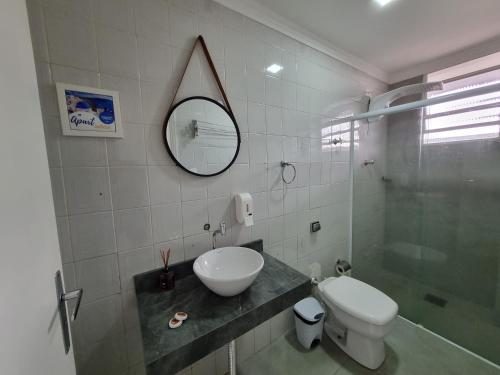 W łazience znajduje się umywalka, toaleta i lustro. w obiekcie Apart Grécia l Aconchego nas Montanhas l Águas de Lindóia w mieście Águas de Lindóia