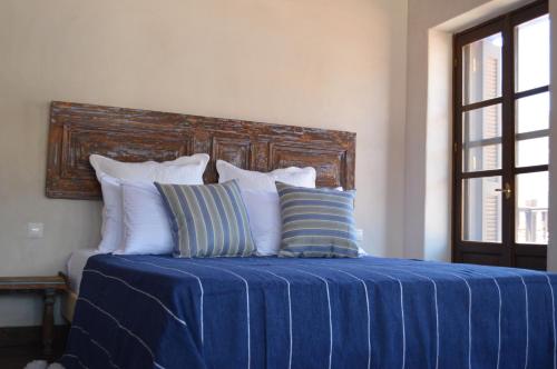 a bed with a blue sheet and pillows on it at Casa Muse Kastellorizo Whole House in Meyisti