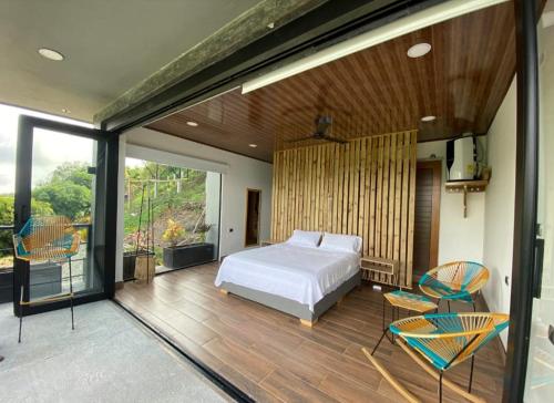 een slaapkamer met een bed en stoelen op een terras bij AVANI Boutique Hotel in Norcasia