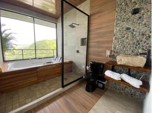 Norcasia的住宿－AVANI Boutique Hotel，一间带浴缸和淋浴的浴室,并设有一个窗户