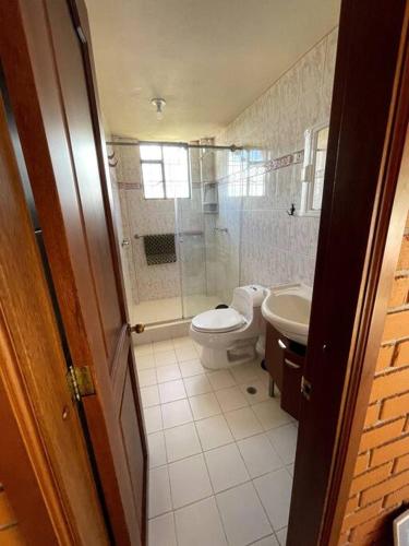 a bathroom with a shower and a toilet and a sink at Hermosa y lujosa cabaña familiar in Chachagüí