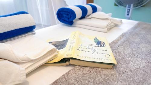 ein Buch auf einem Tisch mit Handtüchern in der Unterkunft The Pool House & The Colobus House, Bella Seaview, Diani Beach, Kenya in Diani Beach